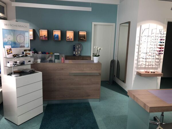 Moderner Empfangsbereich eines Optikers mit Brillenauswahl, Theke und Dekoration.